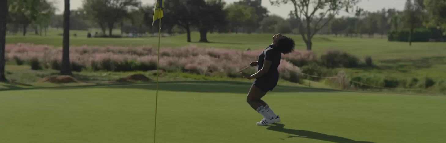 A woman celebrates at the hole on a golf course